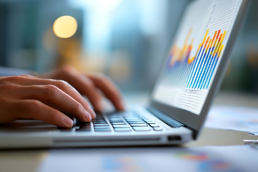 A close-up view of hands typing on a laptop keyboard displaying colorful data charts for an AI workflow integration.